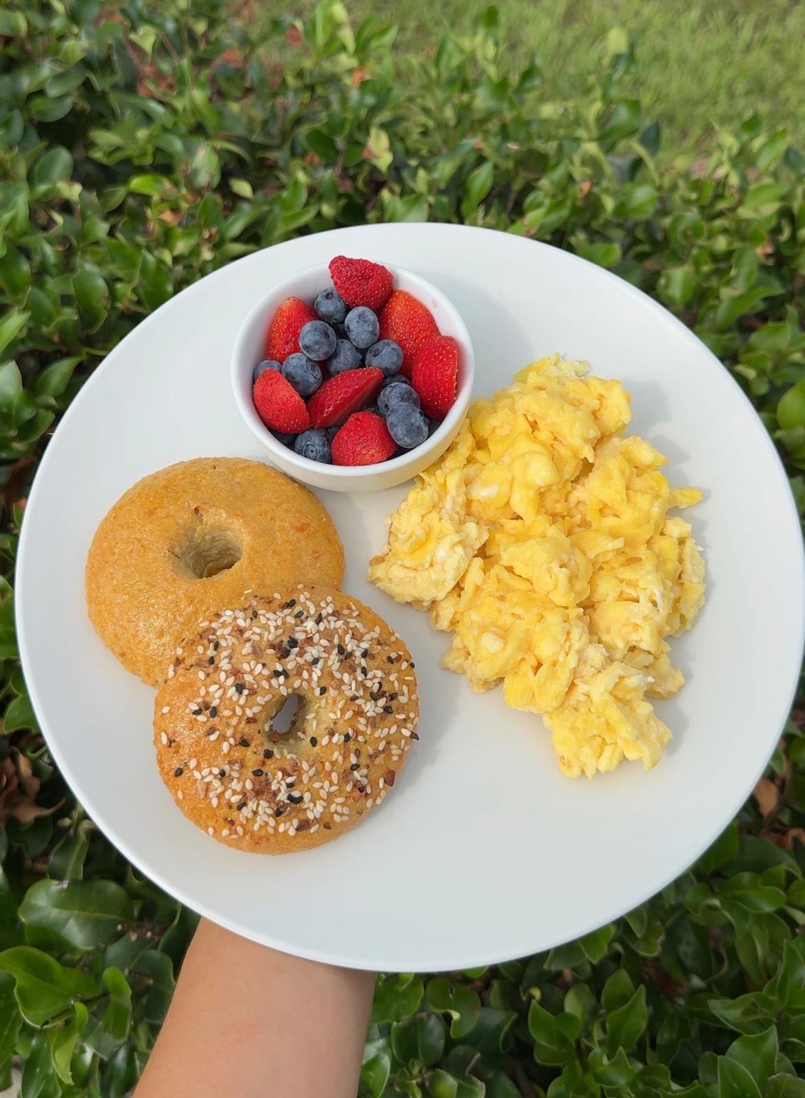 Desayuno saludable con bagels, huevos revueltos y frutos rojos
